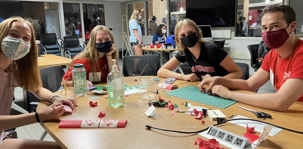 Students sitting at table making laptop stickers.