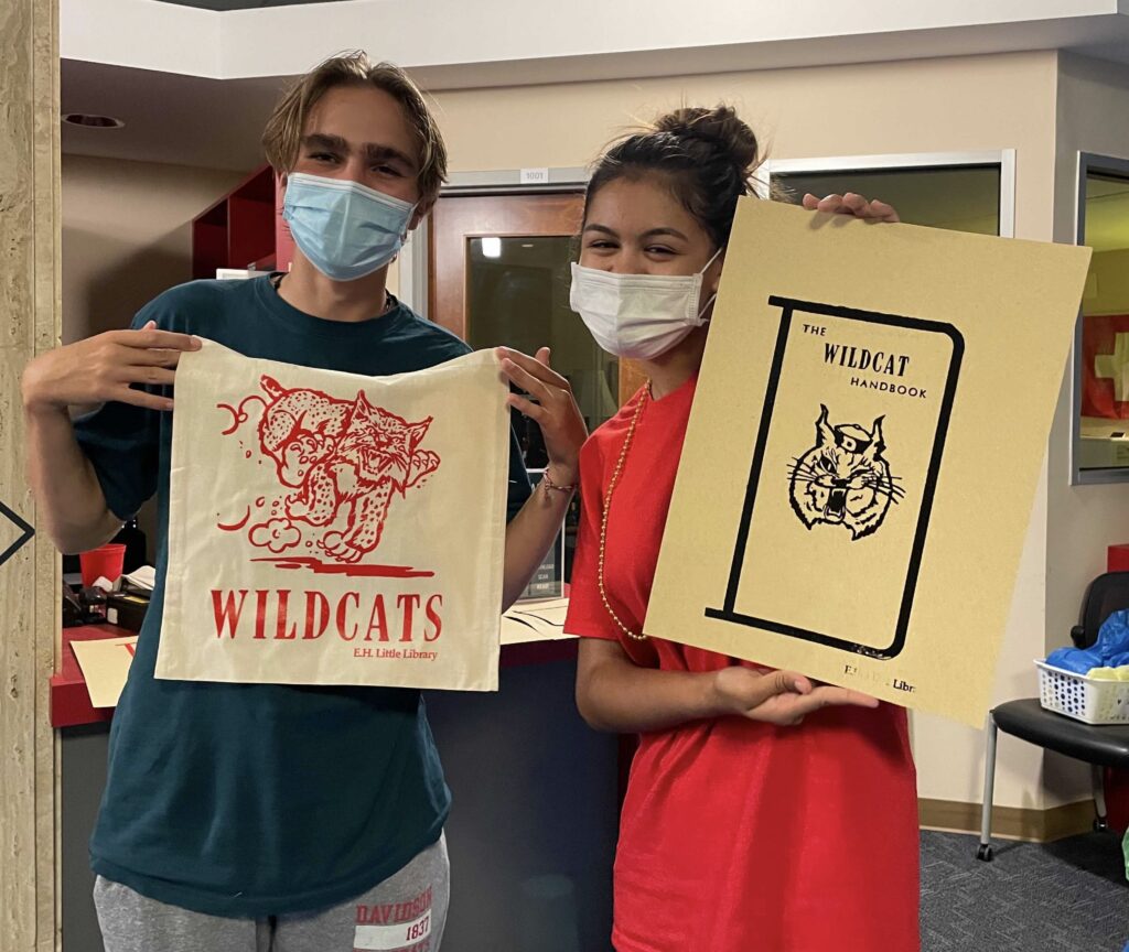 Students holding Davidson Wildcat totebag and poster.