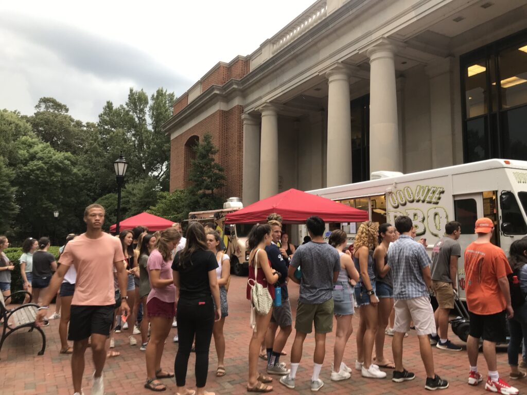 Students lined up at food trucks outside of library.