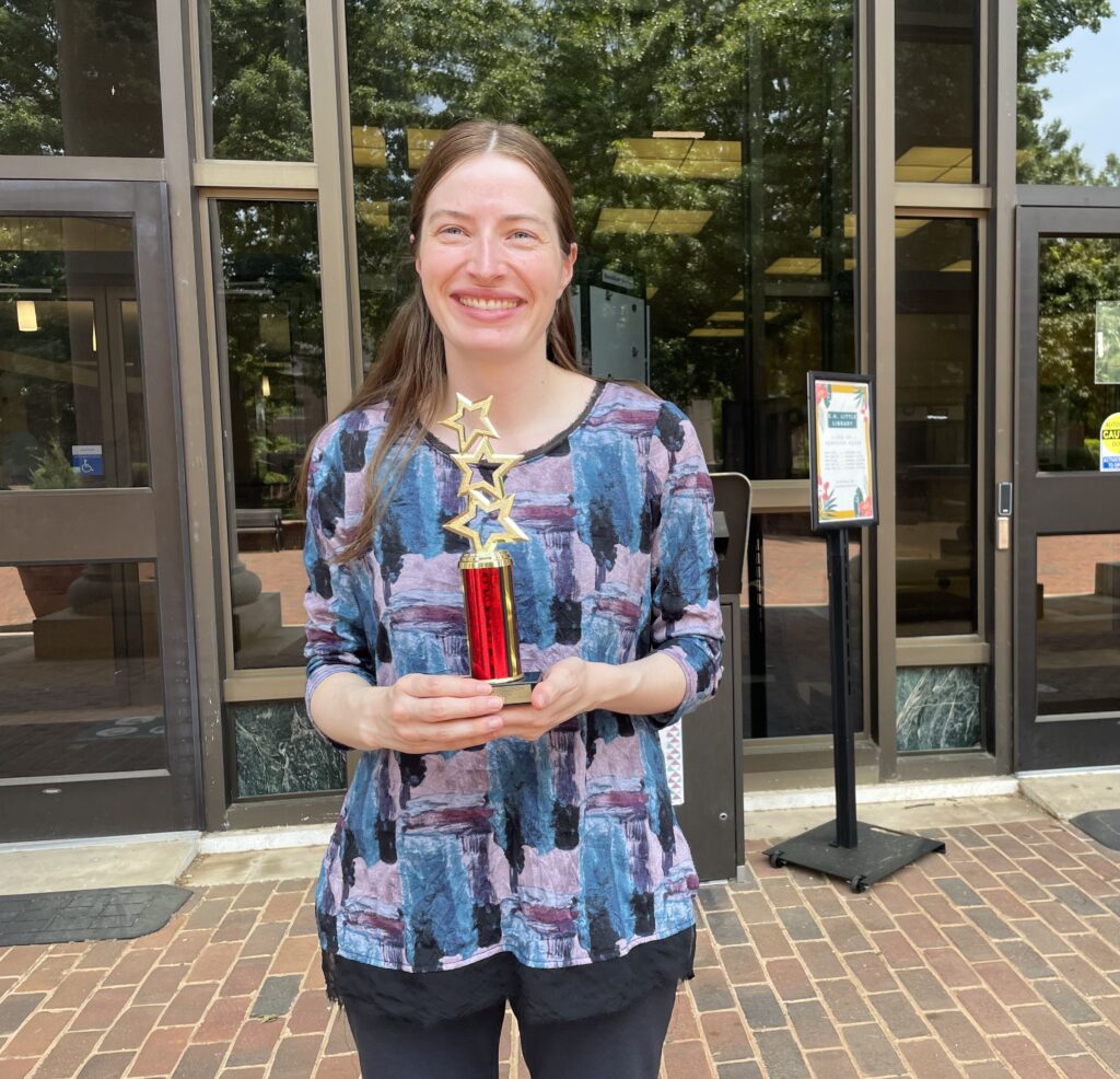 Cara Evanson holding red and gold award with three stars.