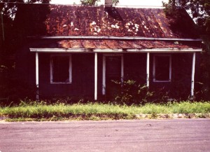 In the foreground is Griffith Street. On the other side of Griffith Street is a brown house withe a brown roof. The porch pillars and window/door trim are white. Number: 2_1_16_3