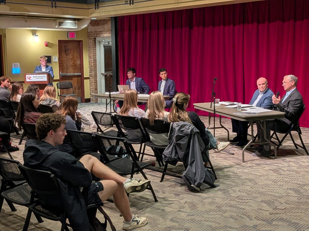 photo of debaters speaking to the audience.