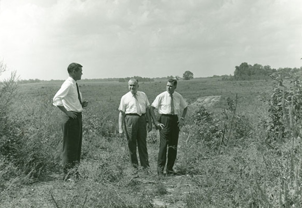 Men studying land around future Lake Campus site
