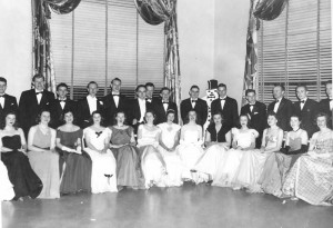 couples at dance, women in front sitting with men standing behind their date