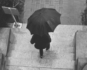 A student leaving Chambers in the rain holding an umbrella