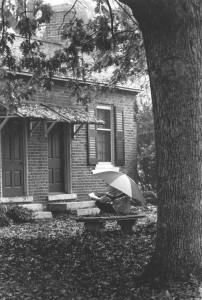 A student studying in the rain with an umbrella near Oak Row in 1998