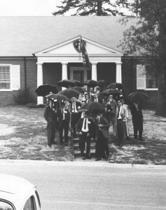 The members of Sigma Phi Epsilon in 1960 outside of their house holding umbrellas in the rain