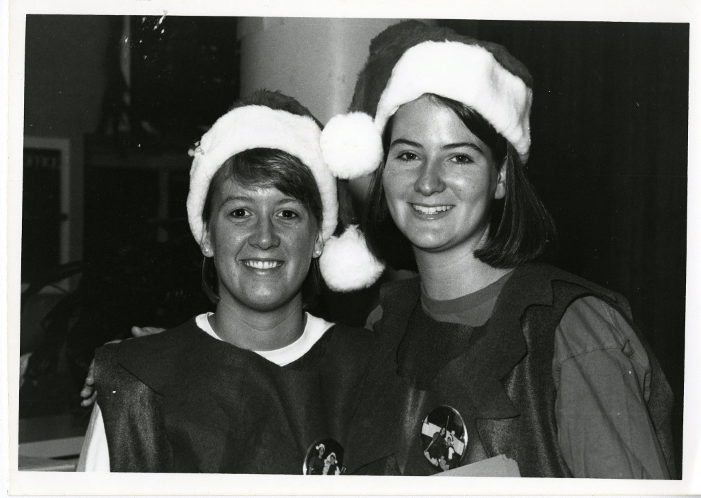 Two unknown students wear Santa hats and holidays pins while in the College Union, 1991.