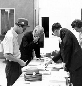 In the 1970s, the alumni office tried out using hats to distinguish classes. A photo of 3 men and a woman standing next to a table looking at hats and papers