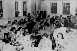 Class gathering inside of a building with the windows open getting ready to eat