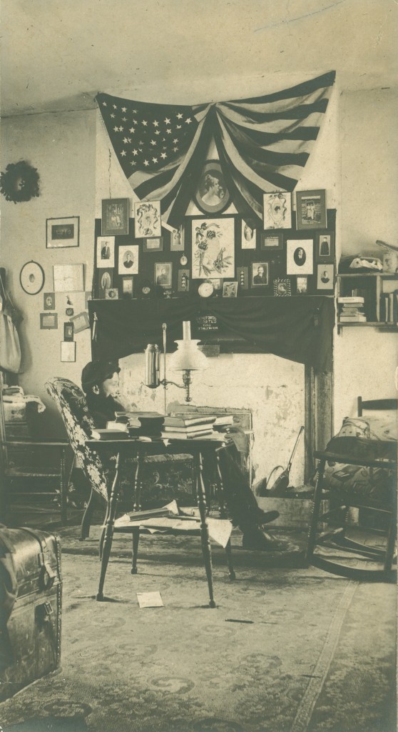 Kemp Elliott Savage (Class of 1906) sits in front of a very elaborately decorated dorm room gallery wall (including a draped flag), circa 1902.