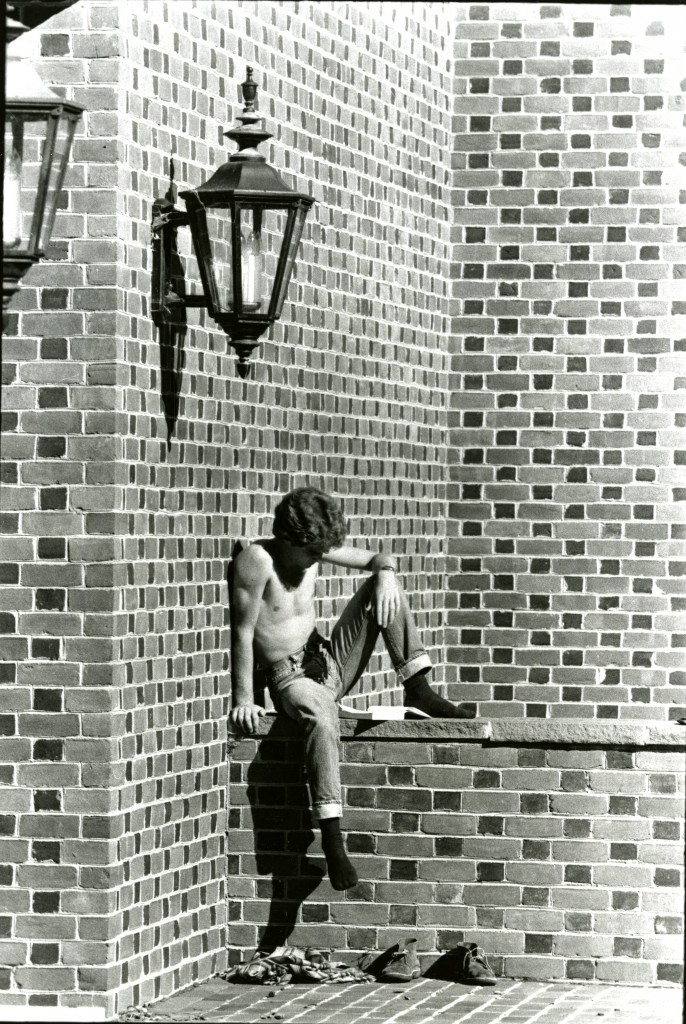 And unknown student with his shirt and shoes(but does have on socks) off studies on a wall outside of E.H. Little Library, during the 1978-79 school year.