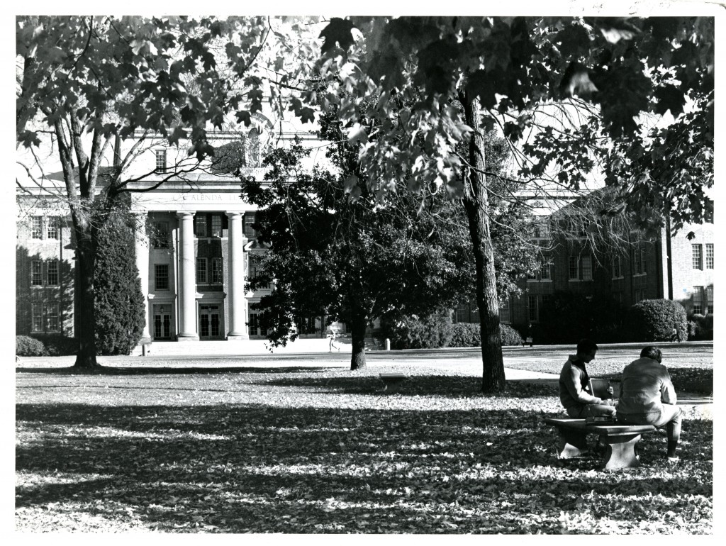 Two unknown students study on a bench with Chambers Building in the background.