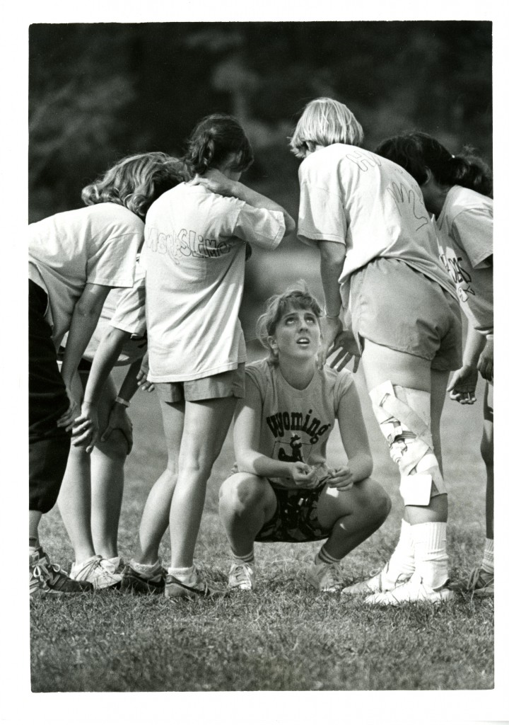 Members of the Rusk House team huddle, fall 1985. One member is squating speaking to the rest of the team.