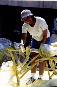 Paula Davis painting the frame of a bike yellow with spray paint