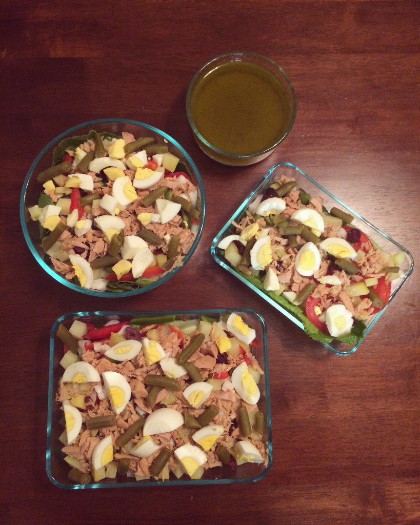 Salade Niçoise in glass containers with vinaigrette on the side. 