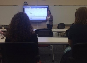 Celia Arch presenting her lesson plans, standing in front of a class next to a projected computer screen