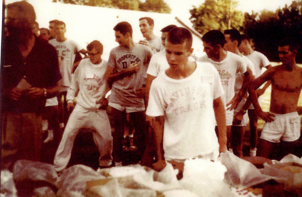 Sterling Martin selecting a cake as his prize for winning the 1959 cake race, while others watch from behind him