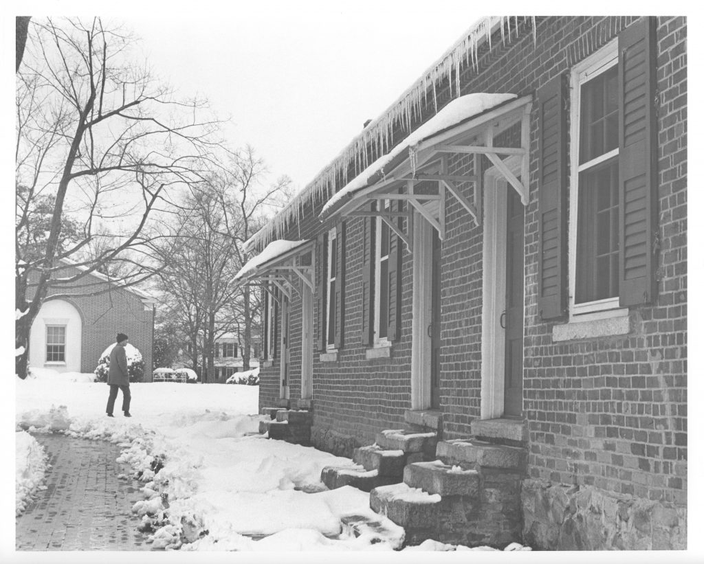 A student walks near Elm Row with many icicles hanging from it, December 1971.