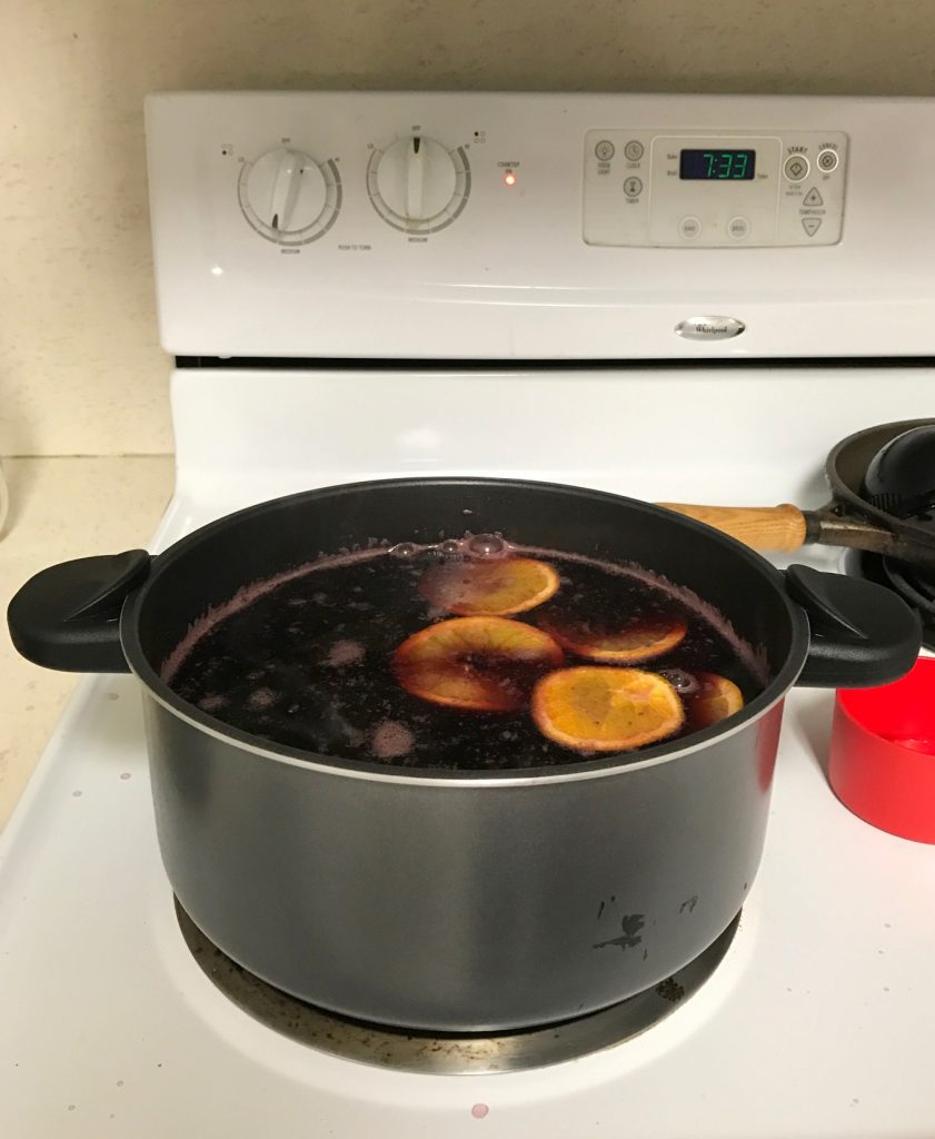 Glogg heating on my stove, complete with orange slices. The time is 7:33 (assuming the stove clock is right)(unkown AM or PM)(unkown date)