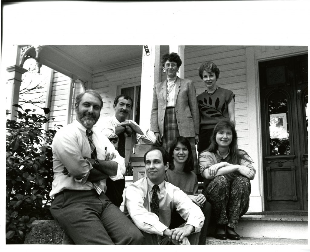 College Communications staff in front of the Copeland House in 1990. From left to right: Jerry Stockdale, Bill Giduz, Pat Burgess, Barbara Mayer, Amy Burkesmith, Michele Miller, and Mike Van Hecke.