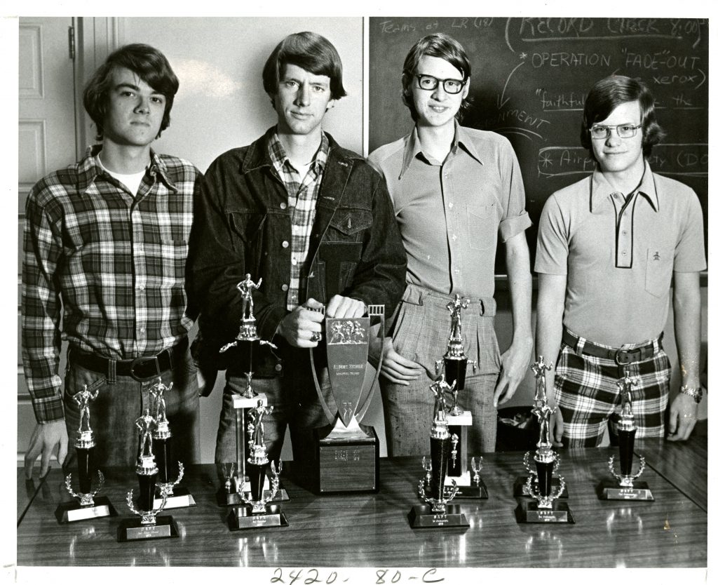 Four members of the debate team stand behind trophies they won in 1975. From left to right: Gordon Widenhouse (Class of 1976), Paul Mitchell (Class of 1975), Mark Gergen (Class of 1978), and Randy Sherrill (Class of 1978).