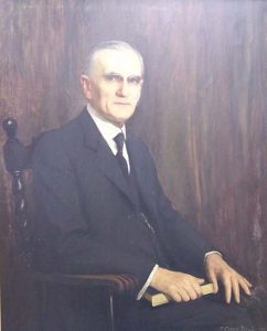 Portrait of Walter Lingle sitting in a chair with a book under his hand