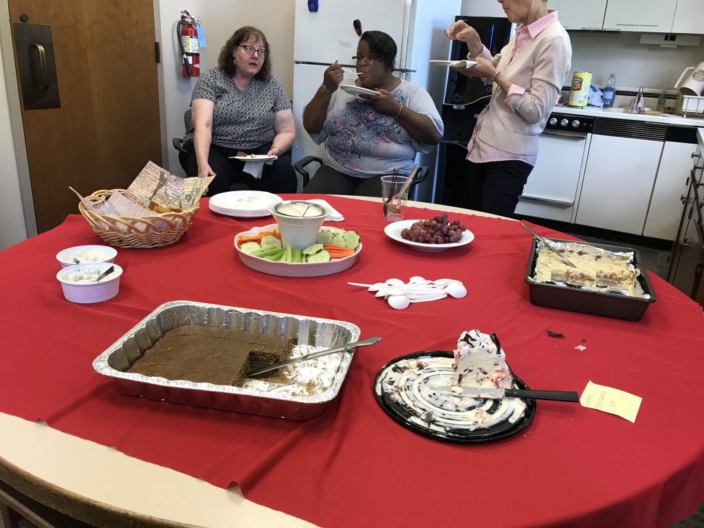 The coffee spice cake on the snacks table during Sarah's party, April 26, 2017. Three people in the background eating.