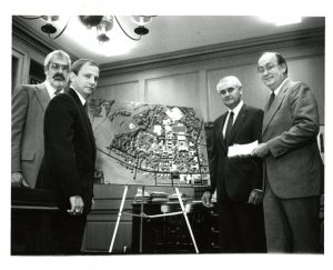 Four men surround new aerial image of the college campus.