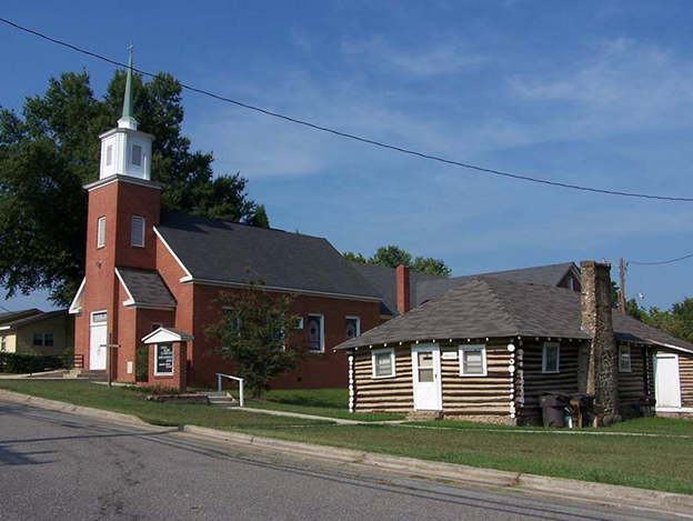 Color photograph of Reeves Temple AME Zion Church in Davidson, NC. To the right of the brick church you will find the Lingle Hut, formerly the mill chapel.