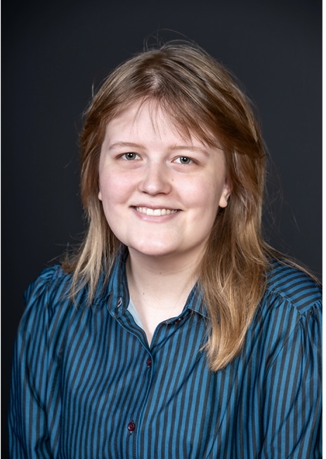 Head shot of Ellen Huggins, JEC Archives Fellow. She is wearing a blue button up shirt and smiling at the camera.