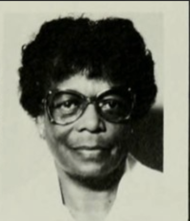 Black and white headshot image of Mabel Torrence. Mabel is wearing large glasses, has short black hair, and is wearing a white shirt. 