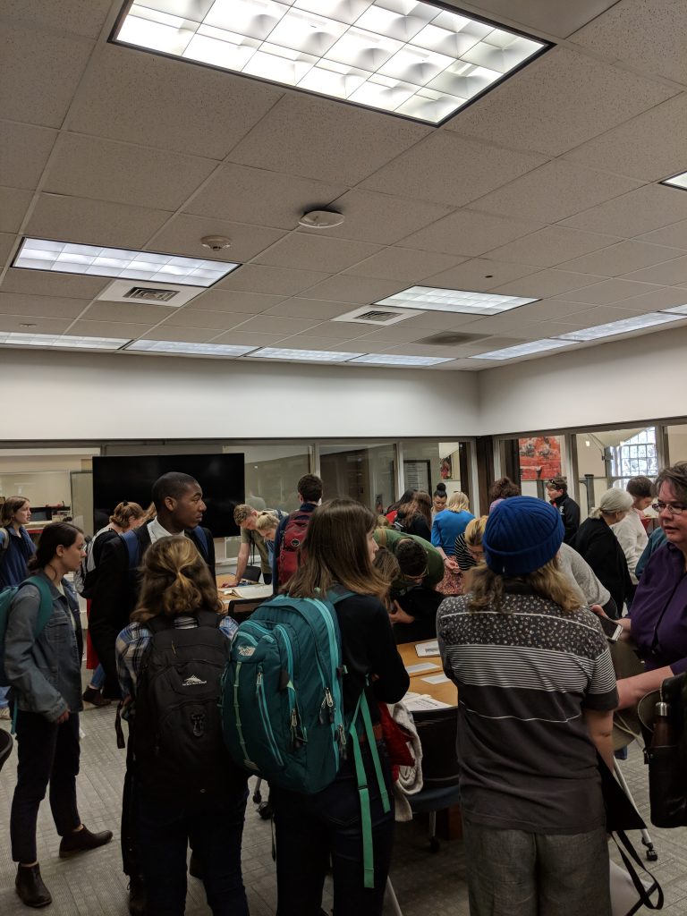 Image of students, townsfolk, and professors interacting with archival materials in the fishbowl as part of the Davidson Disorientation Tour in 2018. 